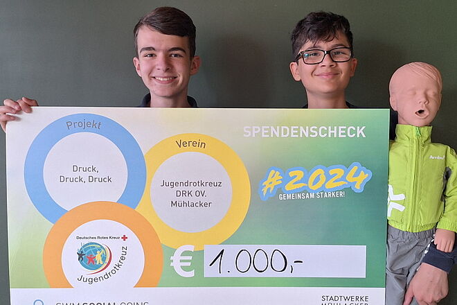 Zwei JRK'ler mit Social Coins-Scheck und Reanimationspuppe "Hugo"