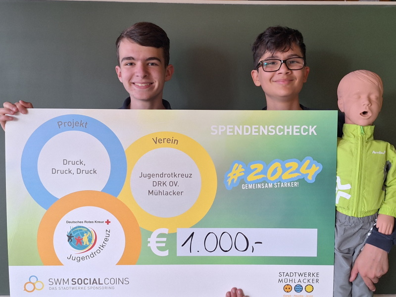 Zwei JRK'ler mit Social Coins-Scheck und Reanimationspuppe "Hugo"
