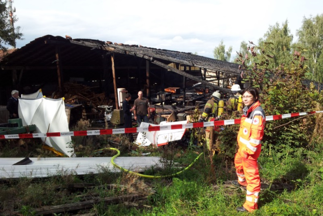 Die Beschädigte Scheune ist abgesperrt. Helfer der Feuerwehr und des DRKs gehen ihrer Tätigkeit nach.
